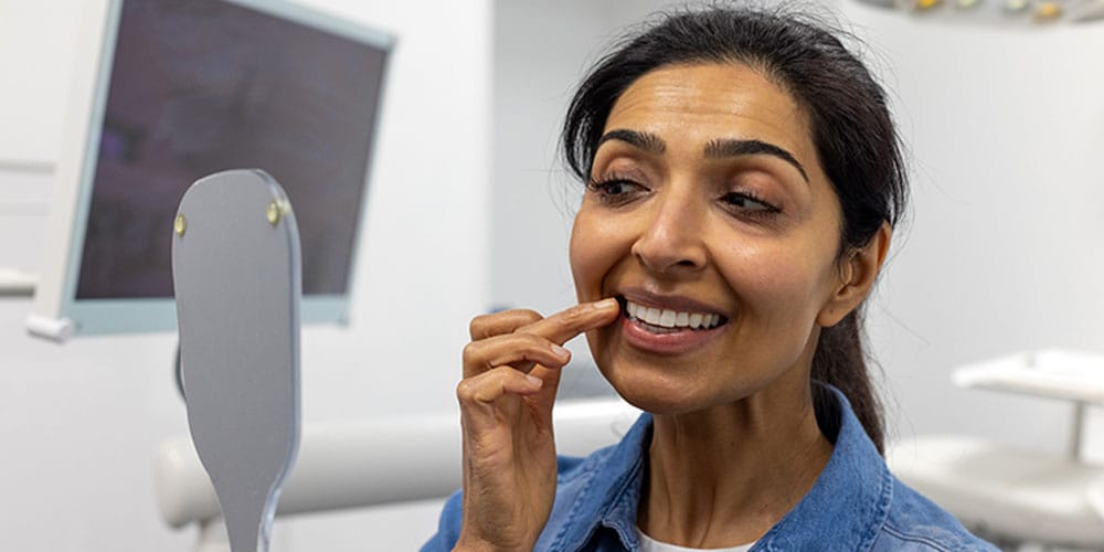 woman looking at her new implants at the dentist in Los Angeles, CA